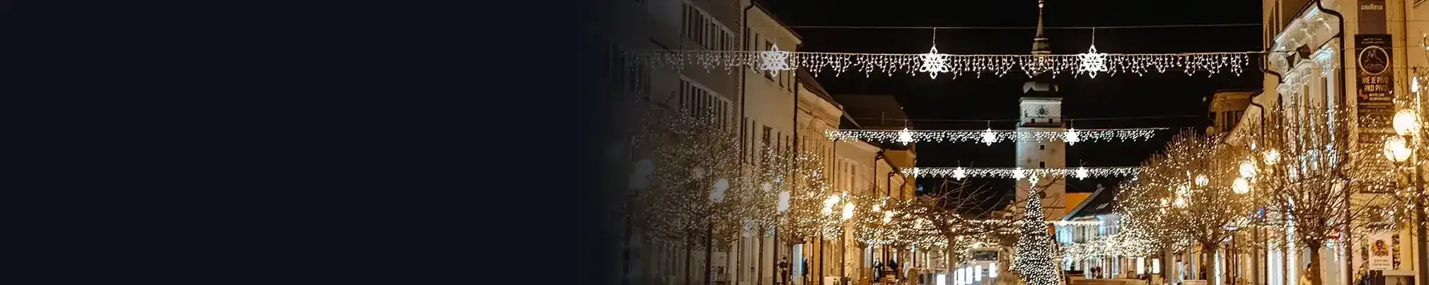 Nočná ulica s vianočnou svetelnou výzdobou cez ulicu a na stĺpoch